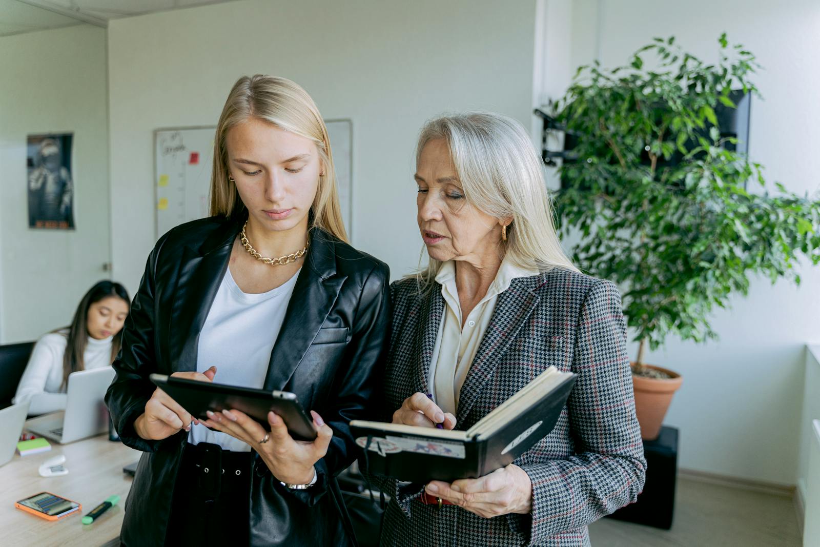 2 Women in Black Suit Jacket Holding Tablet Computer