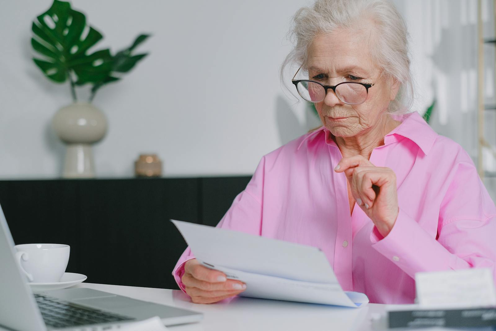 An Elderly Woman in Pink Long Sleeves Looking at Documents while Sitting