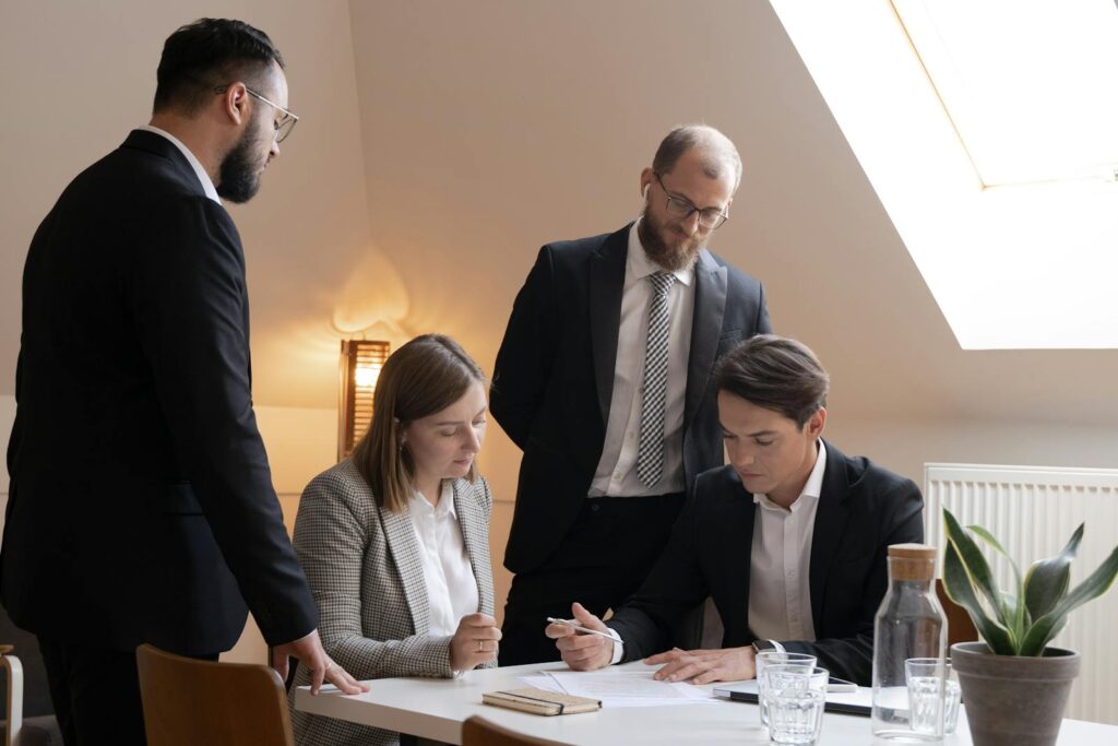 A diverse business team in suits reviewing documents during a meeting indoors.