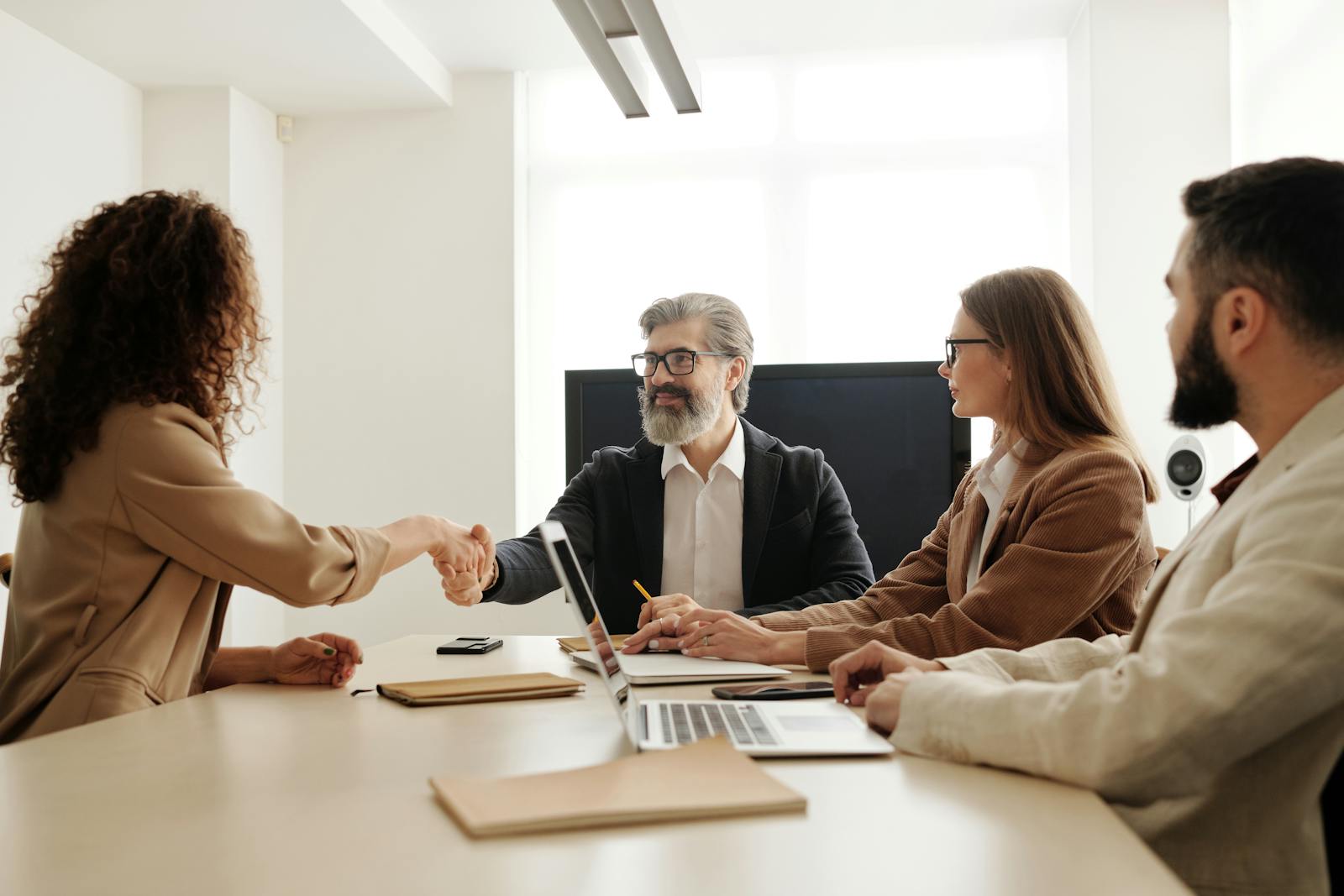 Colleagues in an office celebrating a successful negotiation with a handshake.