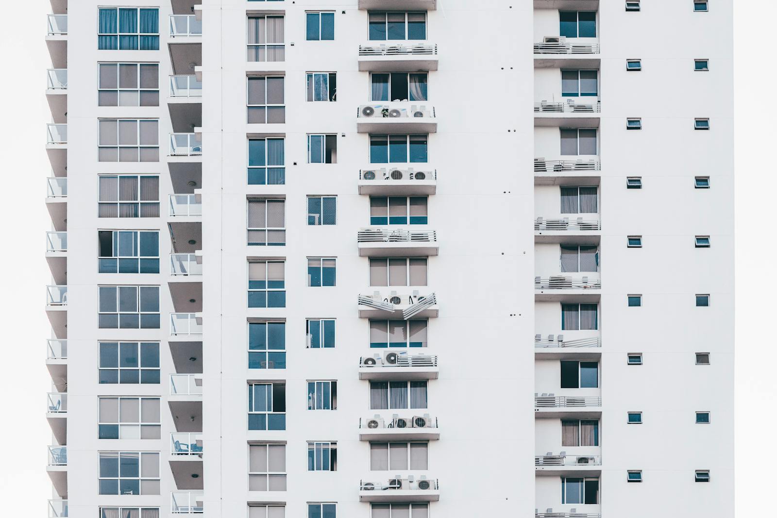 A sleek, modern high-rise building with a glass facade and multiple balconies, showcasing urban architecture.