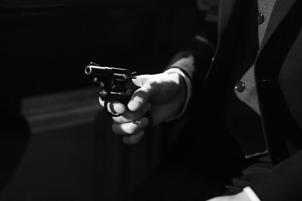 Black and white image capturing a suspenseful noir scene with a handgun.